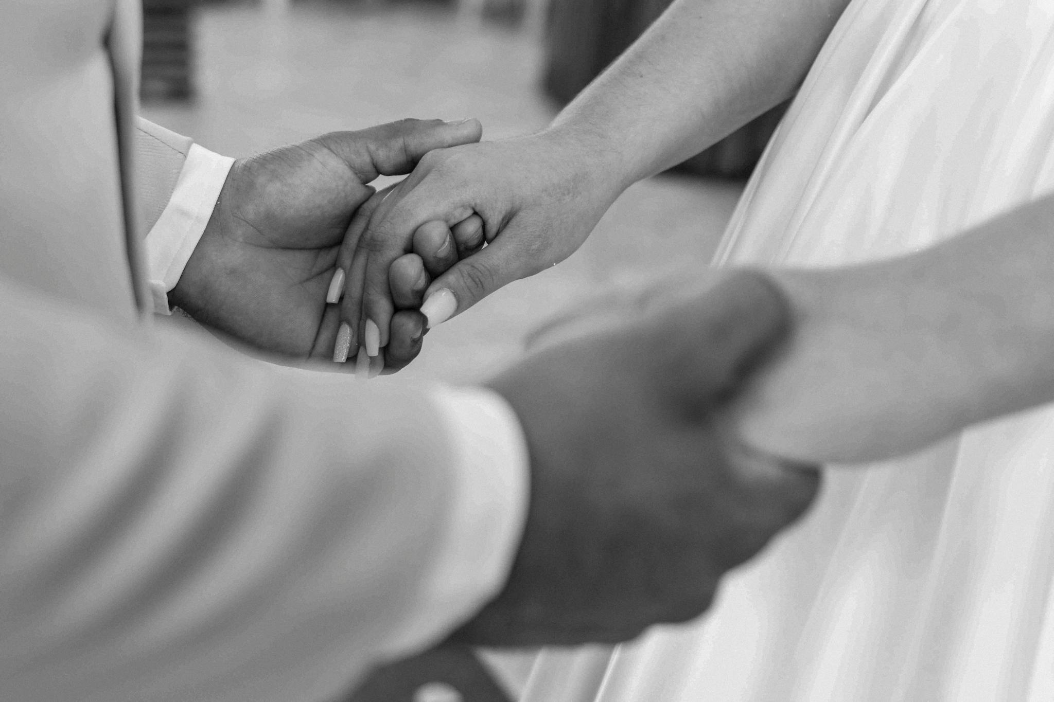 A close-up black and white photo capturing holding hands during a wedding ceremony in Brazil.