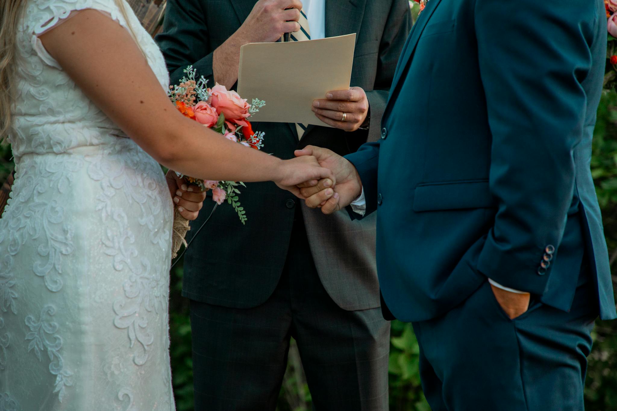 Bride and groom holding hands during outdoor wedding ceremony.