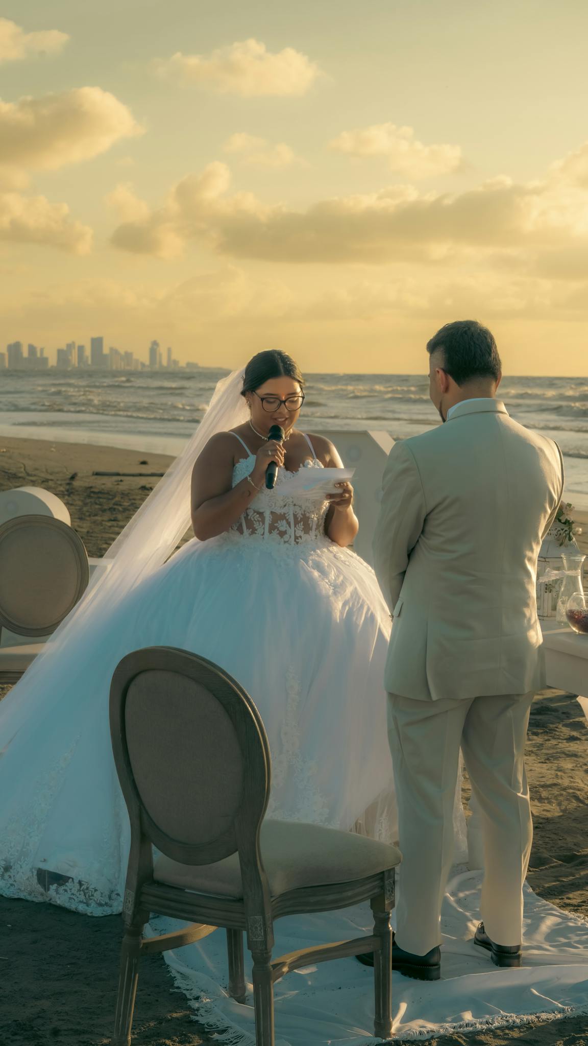 Elegant beach wedding ceremony at sunset with bride and groom exchanging vows.